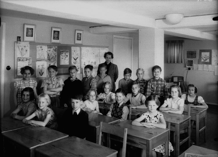 Sven Lindskog, Rostaskolan, klassrumsinteriör, 18 skolbarn med lärarinna fru Eva Risberg. Klass 2å, sal 16.