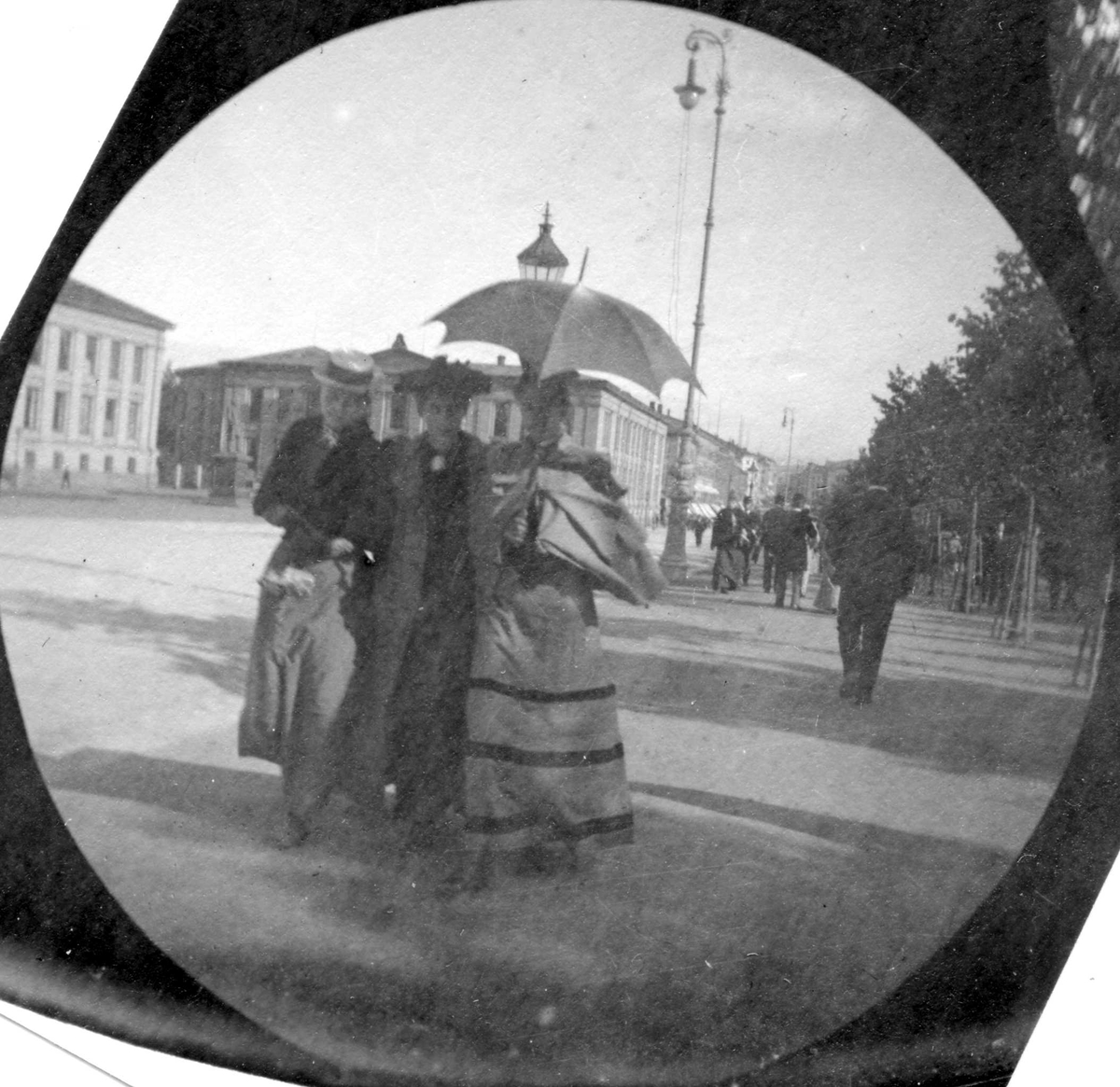 Fredrik Carl Mülertz Størmer, Frk. Smith, Alette Thaulow og frk. Sørbøe spaserer langs Karl Johan, Oslo, Studenterlunden med Universitetet bak.