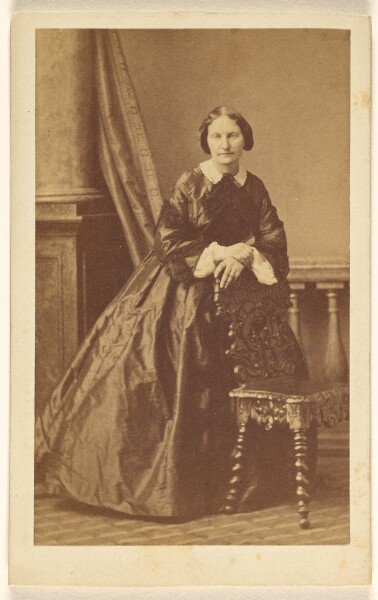 Disdéri & Cie., [Unidentified woman standing, leaning on chair back]