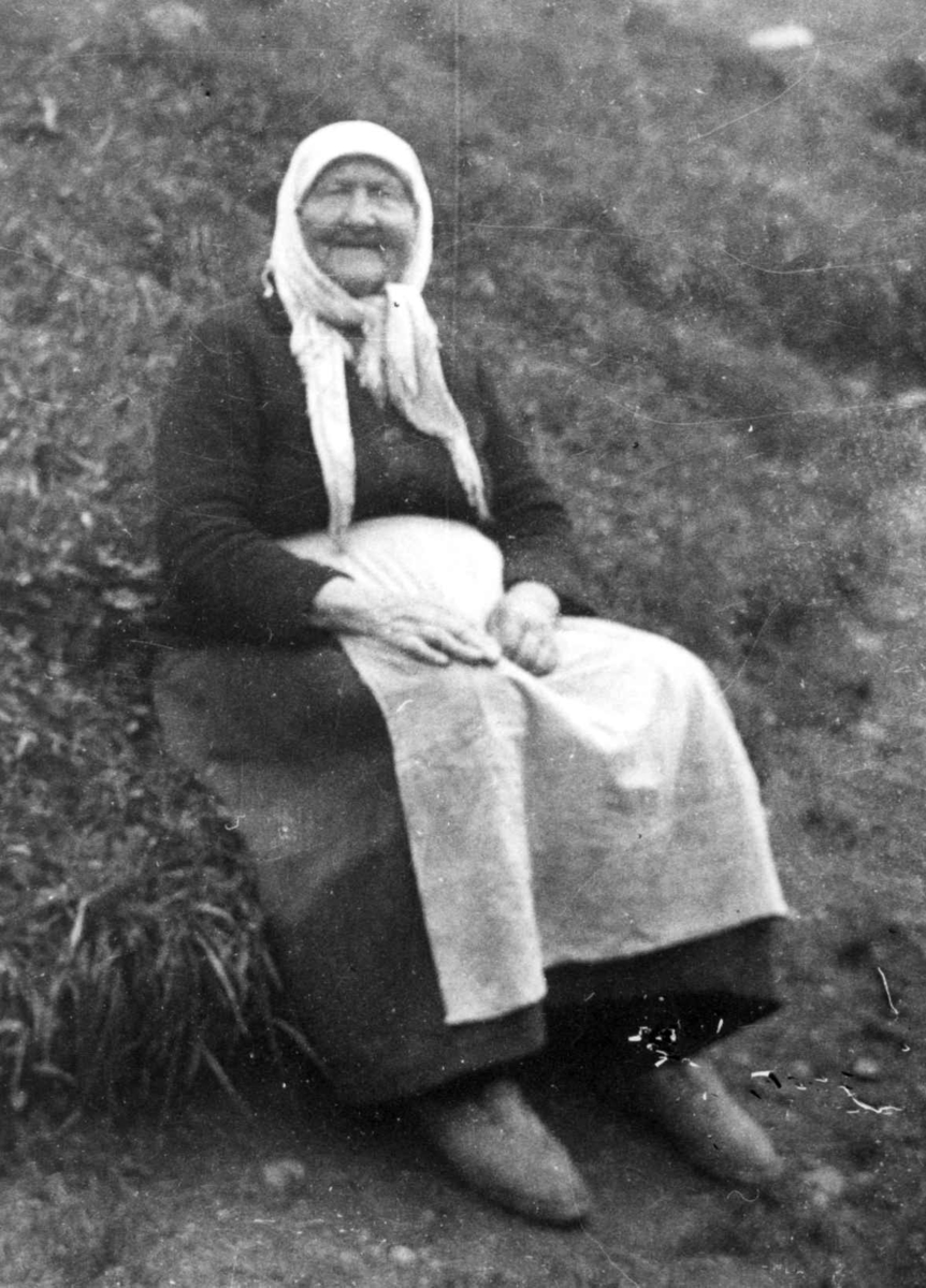 Anna Grostøl, Fru Randi Tveiten sitter på en gressbakke. Eiken, Hægebostad, Vest-Agder 1937.
