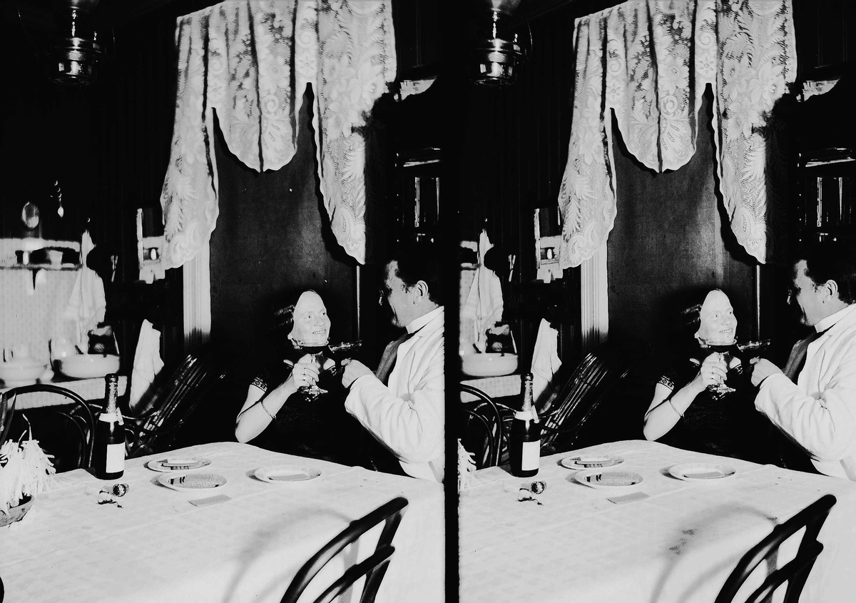 Axel Quinsgaard Wiborg, Interiør, mann og kvinne sitter ved bord og skåler, Axel Q. Wiborg med antatt sin kone Margrethe. Vaskestell i bakgrunnen. Ukjent sted.