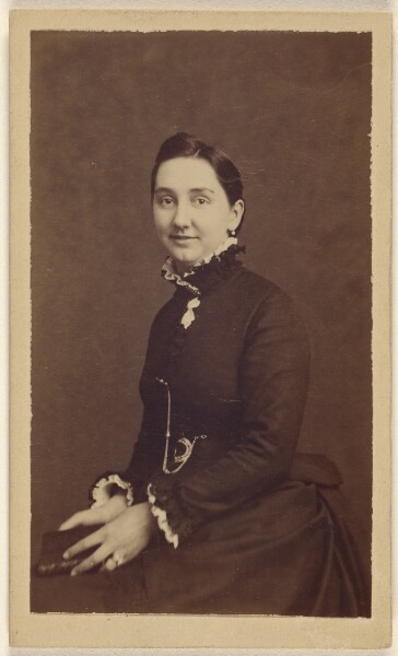 Unknown, [Unidentified woman wearing a dark dress, holding a book, seated]
