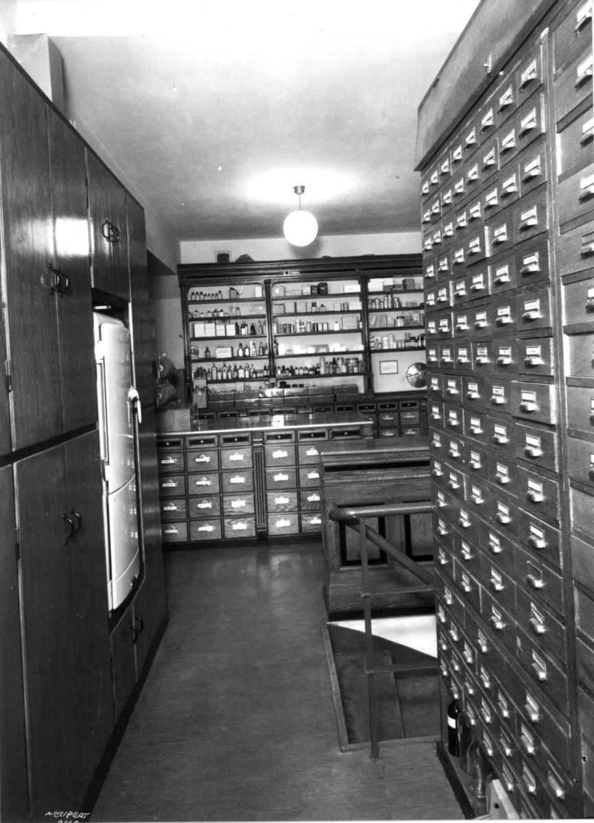 Hermann Christian Neupert, Rådhusapoteket, Oslo 1937. Materialkammer. Skap. Hyller. Skuffer. Flasker