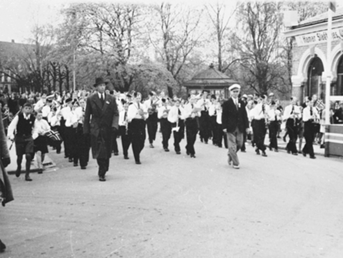 Anno Domkirkeodden, 17 MAI TOGET FORAN BASARBYGNINGEN MED HAMAR GUTTEMUSIKKORPS MED DIRIGENT HALFDAN HANSEN, KIOSKEN I STRANDGATEPARKEN I BAKGRUNNEN