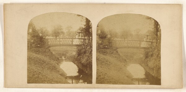 Unknown, [Woman crossing footbridge over stream]