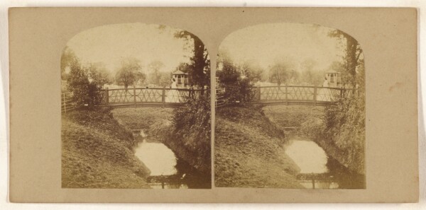 Unknown, [Woman crossing footbridge over stream]