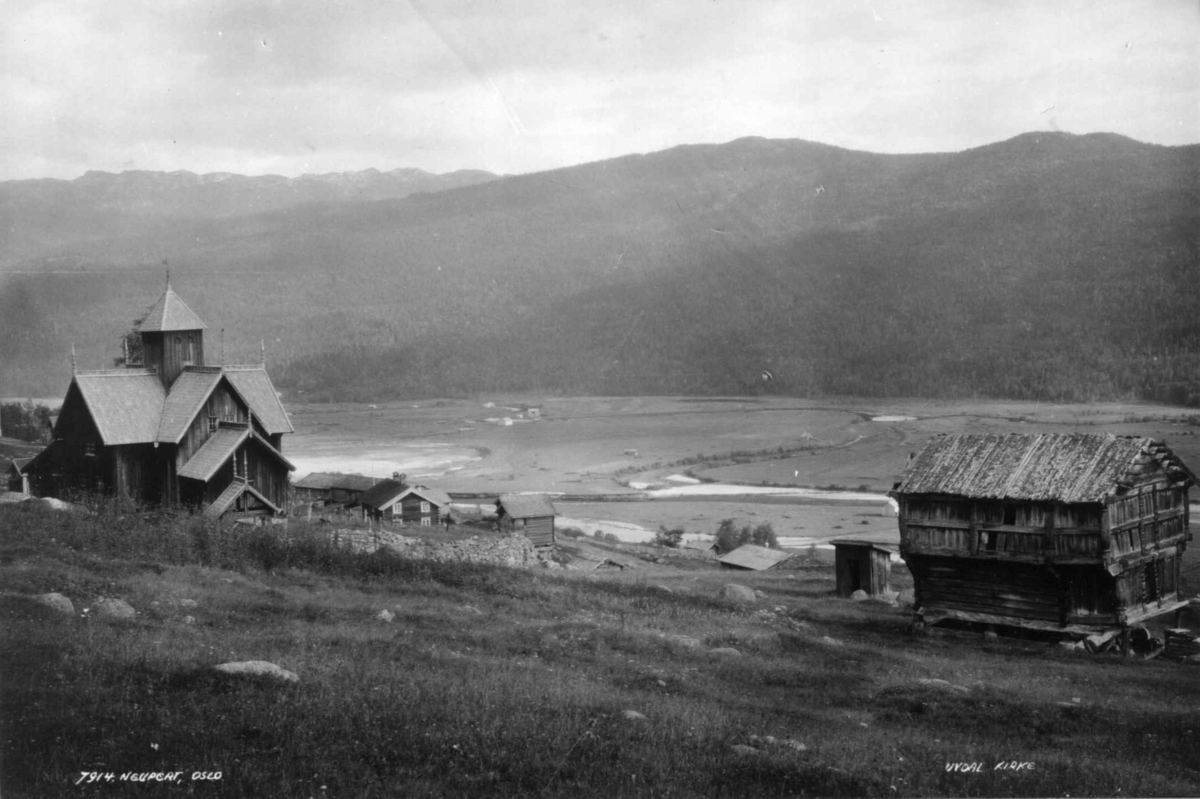 Hermann Christian Neupert, Uvdal kirke, Nore og Uvdal. 1930. Oversiktsbilde. Husebygårdene i midten. Prestegårdstabburet til høyre. Landskap med jorder, åser og fjell i bakgrunnen.