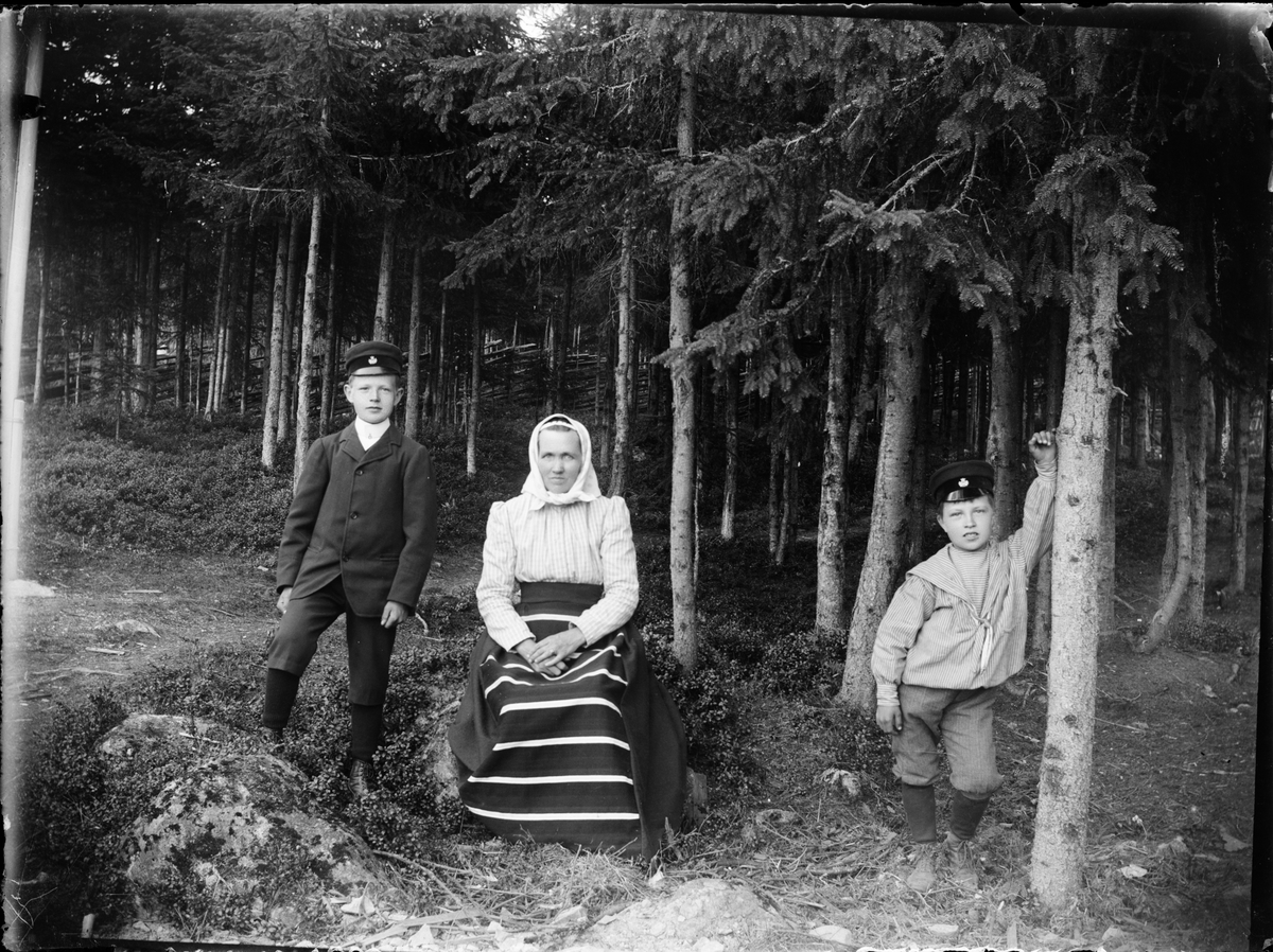 Skötsner-Edhlund, Kvinna i folkdräkt och två pojkar i skogsmark, Dalarna