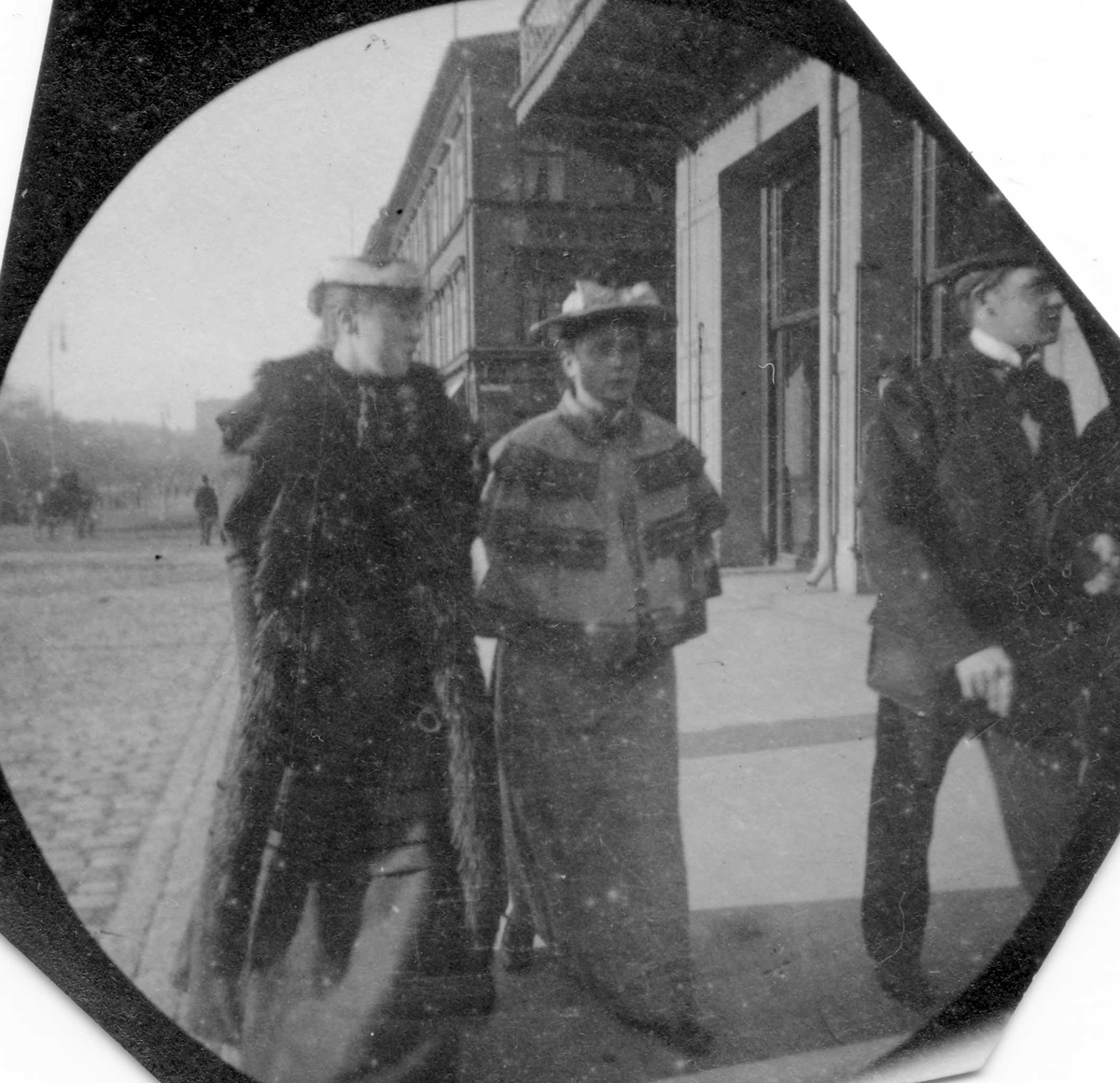 Fredrik Carl Mülertz Størmer, To kvinner og en mann i bygate, ant. Karl Johans gate, Oslo.. Bygårder bak.