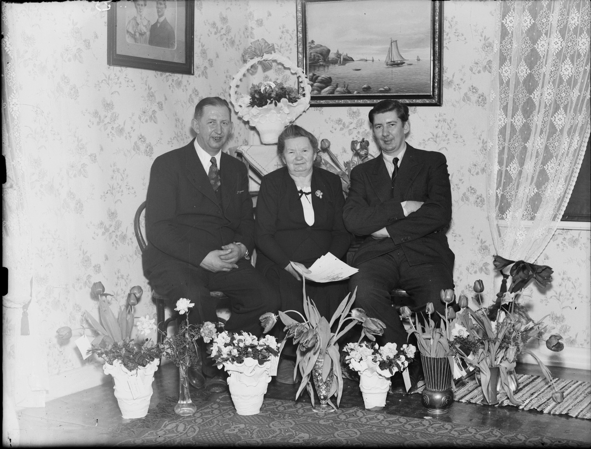 Skötsner-Edhlund, Hotellägare Ivar Janssons fru och två män omgivna av blommor, Östhammar, Uppland