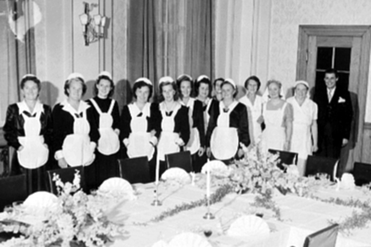 Anno Domkirkeodden, GRUPPE 11 SERVERINGSDAMER, DEKKET BORD I FESTIVITETEN, FRA VENSTRE: INGEBJØRG SOLHEIM, GINA MOSTUE, MAGDA EVENSEN, GINA HALVORSEN, DORTHEA HÅBERG, JORUNN MIKKELSEN, SIGNE HANSEN, BAK: JENNY HEIBERG, MARTHA BROVOLD, ELLEN COCOZZA, KRISTINE LIAKER, GUDRUN ARNESEN OG DIREKTØR GULBRAND SØBERG