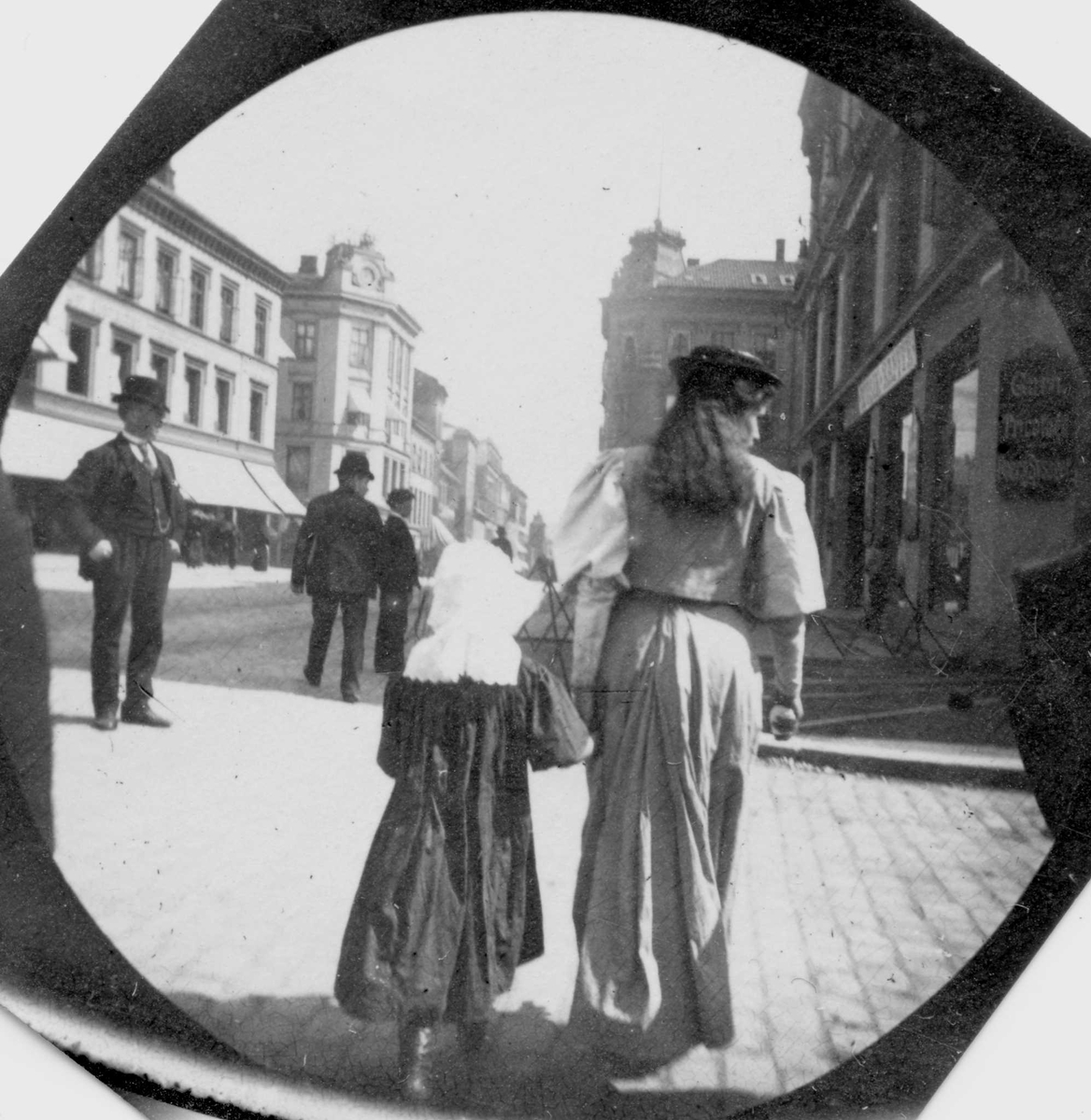 Fredrik Carl Mülertz Størmer, Frk.Martha Arneberg og ei lita jente spaserer langs Karl Johan, Oslo med ryggen til fotografen i retning mot Egertorget.