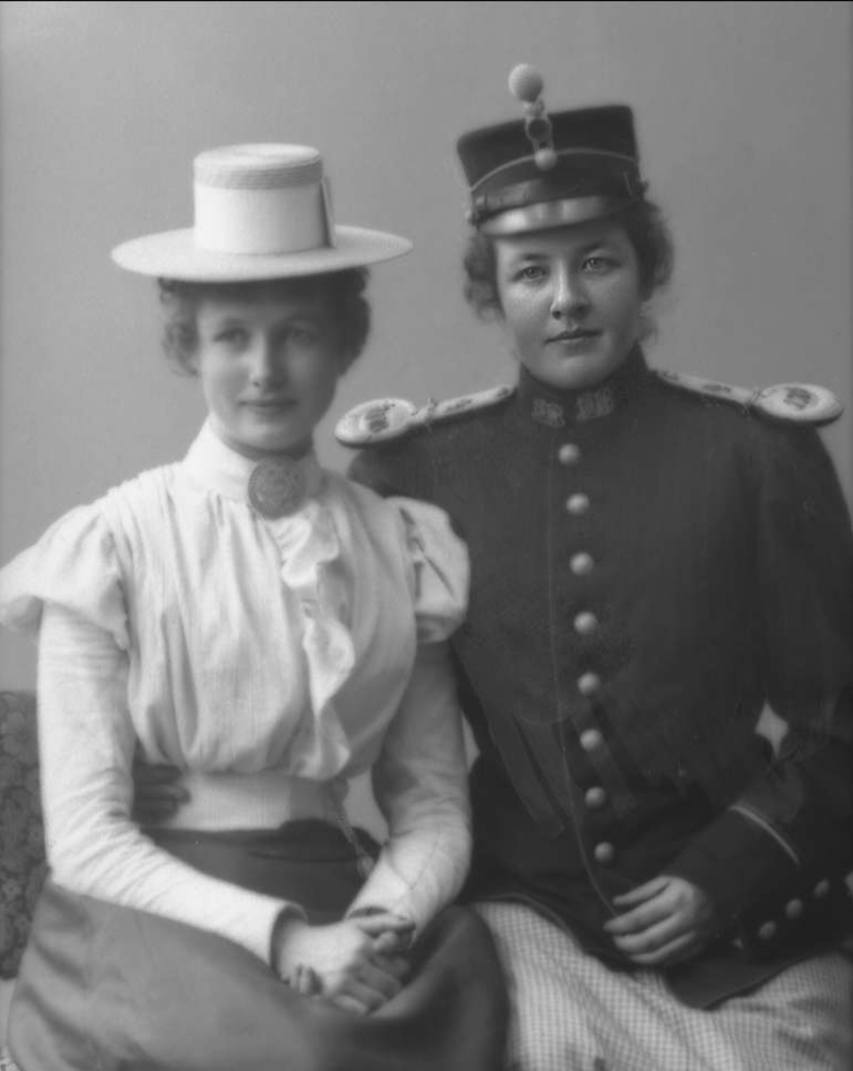 Gustav Borgen, Gruppeportrett, to unge kvinner. Den ene utkledd i militær uniformsjakke og lue.