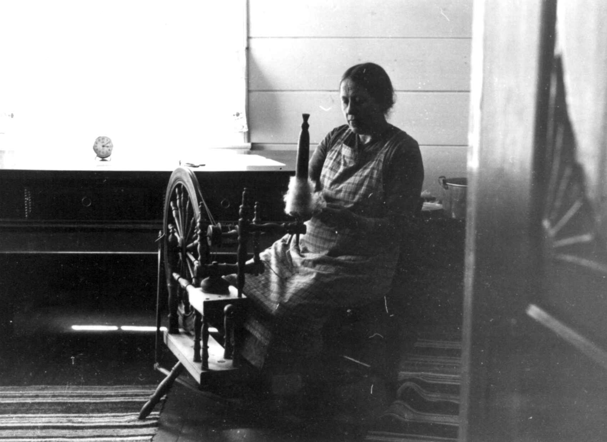 Anna Grostøl, Fru Bjartland sitter ved rokken og spinner til vadmel. Bjelland, Marnardal, Vest-Agder 1939.