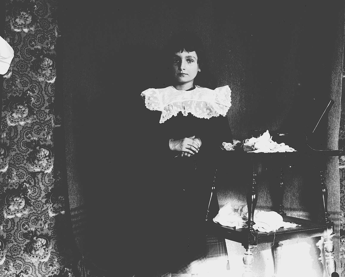 Axel Quinsgaard Wiborg, Karen Q.Wiborg står ved et bord, Munkedamsveien 3, Oslo, 1903.
