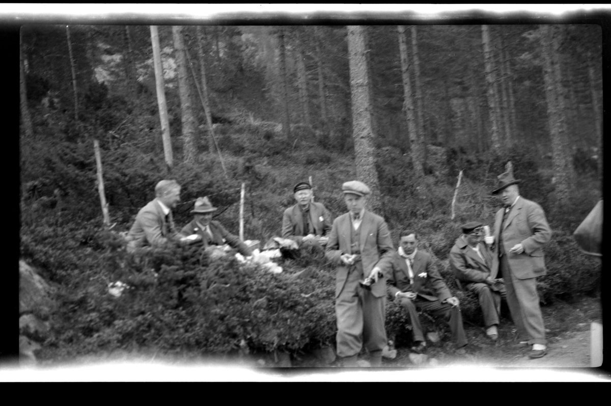Rolf Sr. Sundt, En gruppe menn, familie og venner, raster i skogen. Fra venstre Peter Sundt, ukjent, Christen Reymert, Bjarne Sundt, Johan Buratti, ukjent og Trygve Sundt. Fotografert mai 1928.