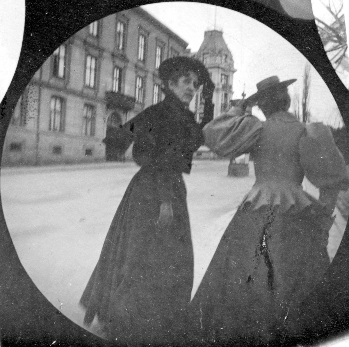 Fredrik Carl Mülertz Størmer, Frk. Brodkorp og en annen dame spaserer langs bygate, Oslo. Den ene holder på hatten.