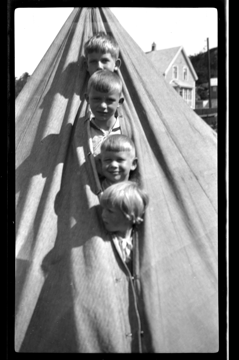 Rolf Sr. Sundt, Fire gutter titter ut av teltåpning. Øverst Rolf Sundt Jr, deretter Arne og Sven Moestue og nederst Lars Peter Sundt. Fotografert i Ula, Vestfold 1932.