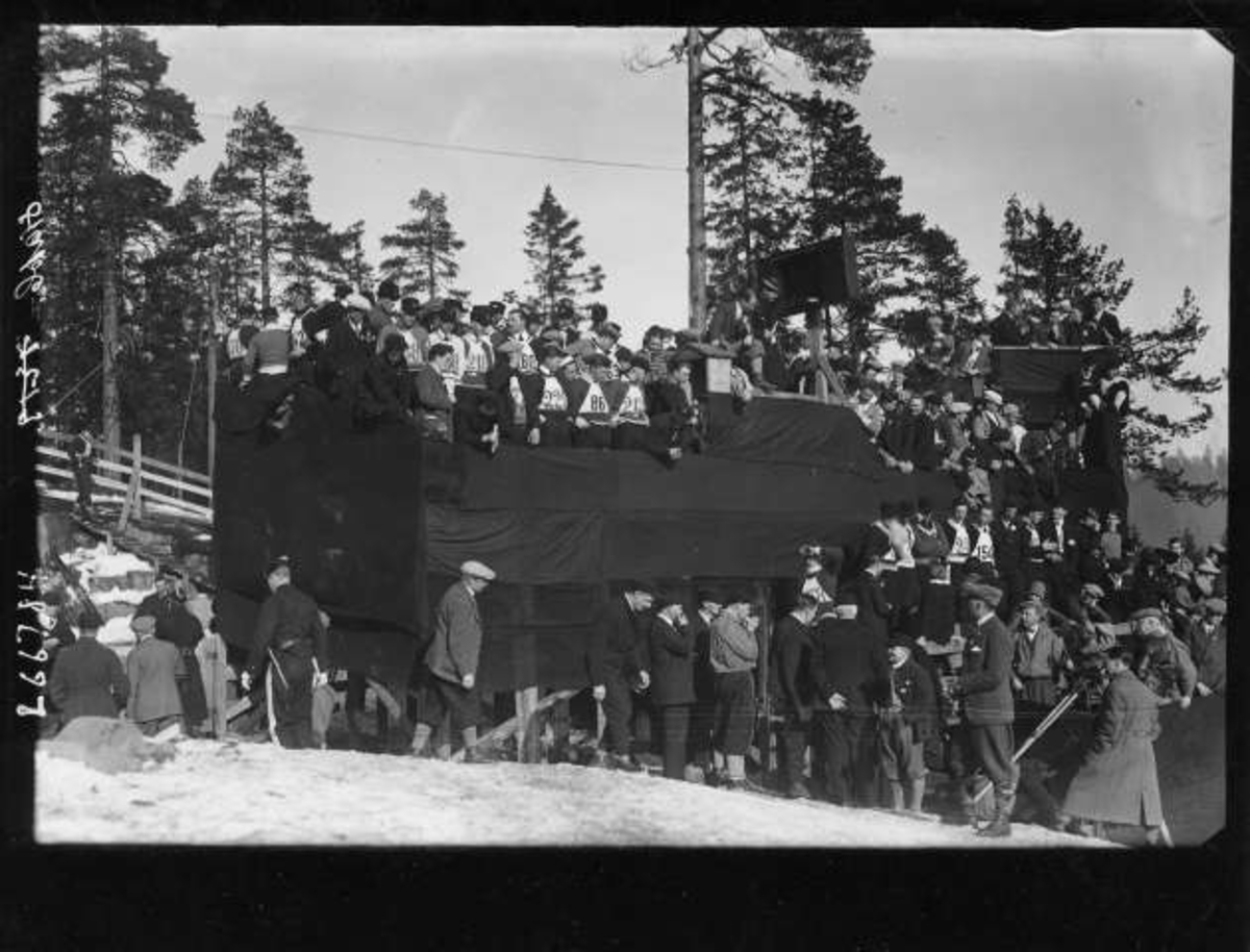 Hermann Christian Neupert, Menn med deltagernummer og tilskuere på en tribune. Holmenkollen?