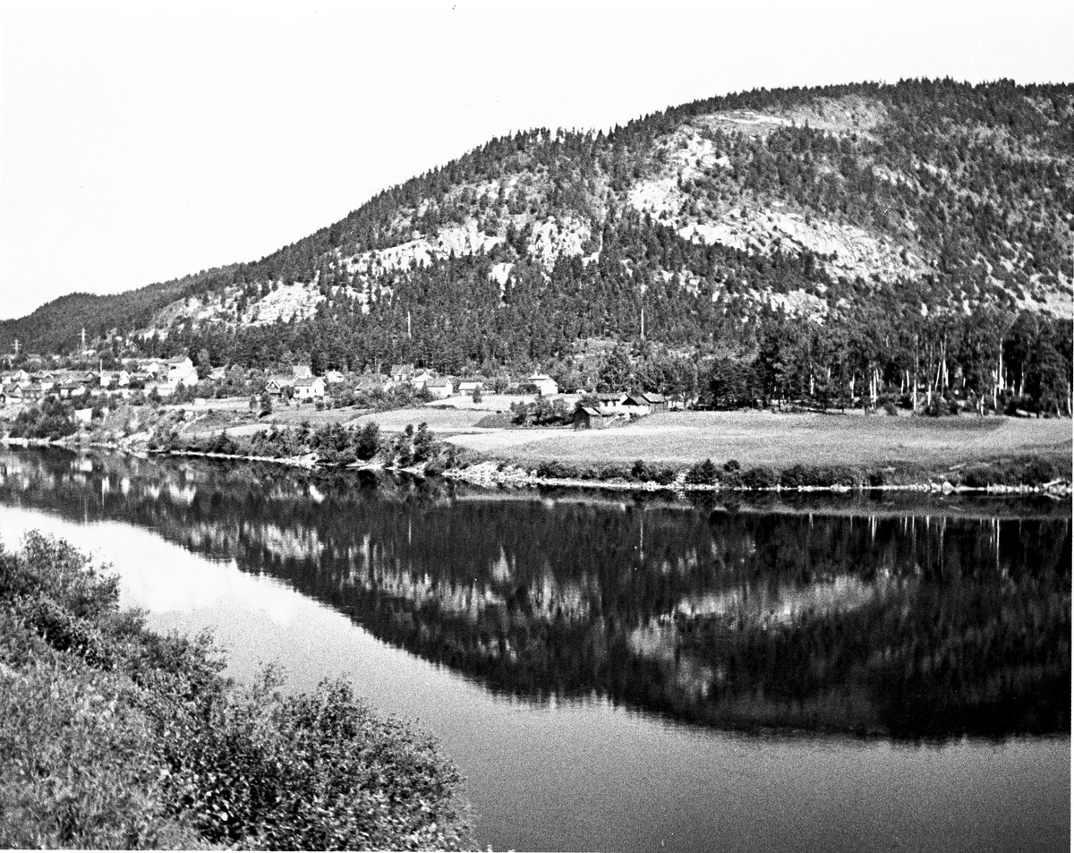 Anders Beer Wilse, Landskap med gårdsbruk og åkre ved en elv. Antatt Mjøndalen. Fotografert 1940.