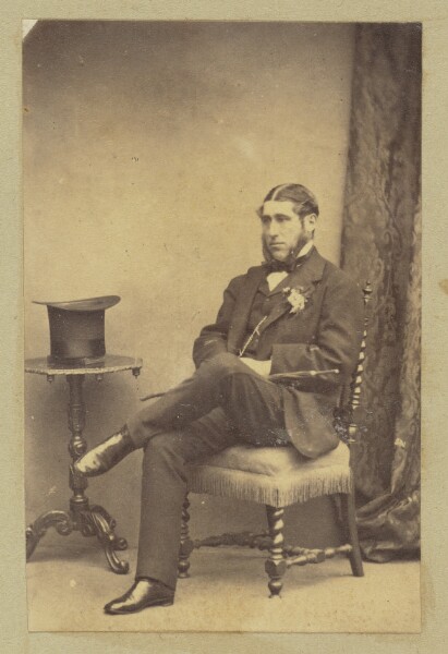 Unknown, [Portrait of seated man with top hat on table]