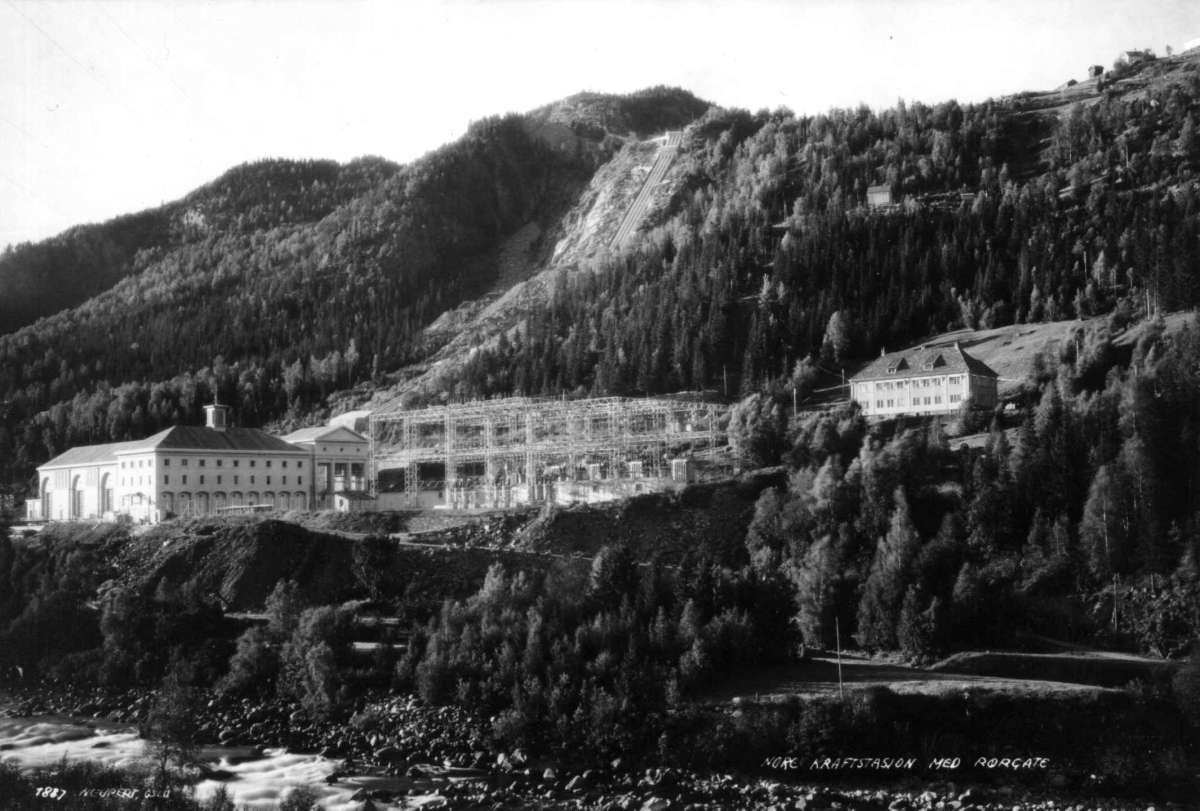 Hermann Christian Neupert, Nore kraftstasjon, Nore, Nore og Uvdal. 1930. Oversiktsbilde. Kraftgate. Skog og fjell i bakgrunnen. Beggyelse. Vei og elv i forgrunnen.