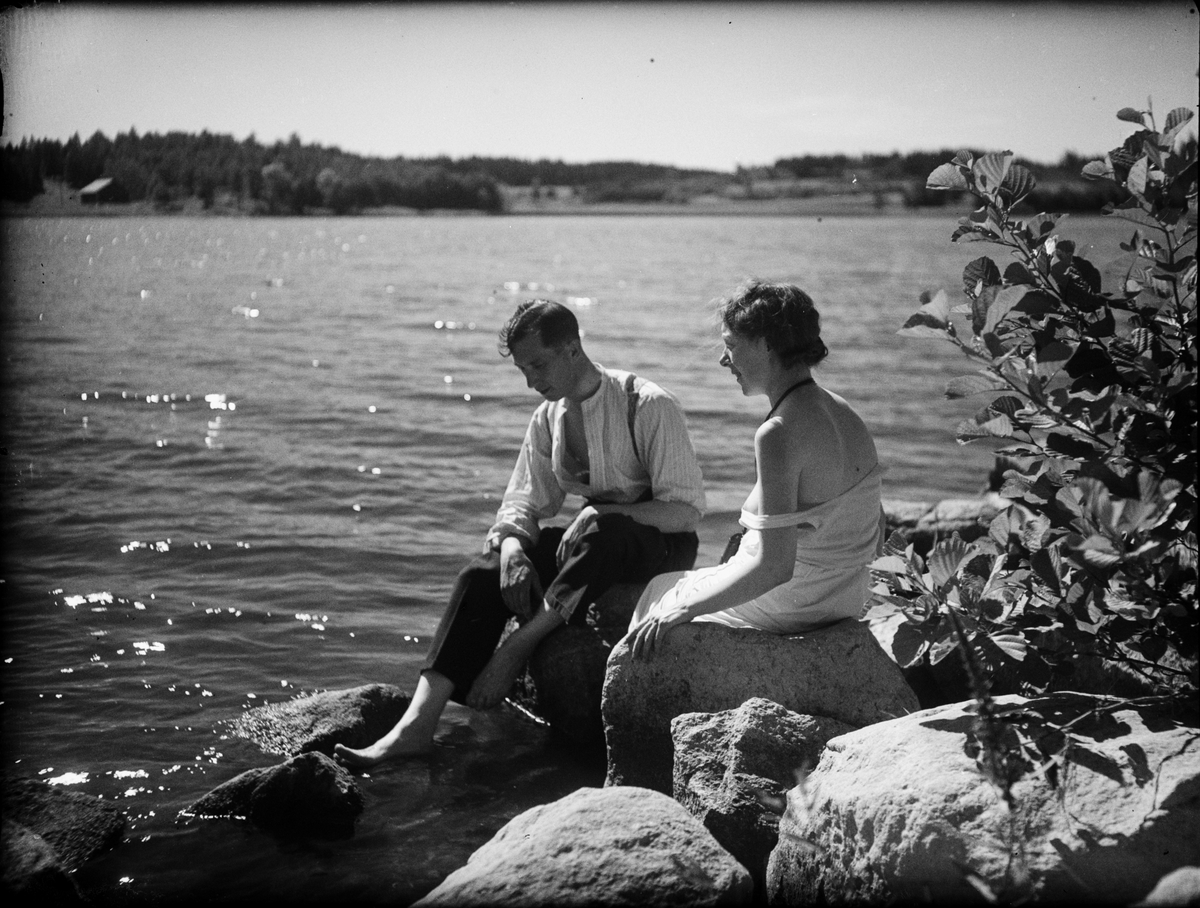 Skötsner-Edhlund, Man och kvinna sittande på stenar vid vattnet , Östhammar, Uppland