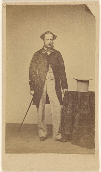 Unknown, [Unidentified man with walking stick, standing near table with top hat]