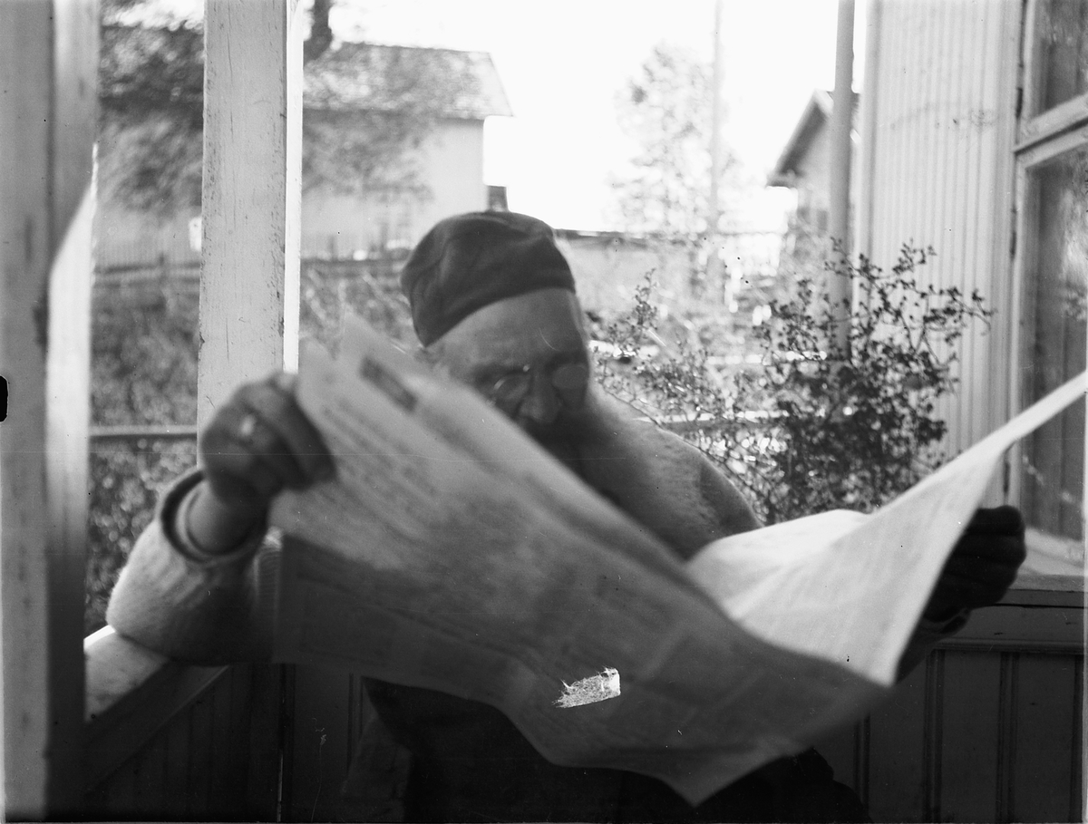 Ragnvald Andersen, Eldre mann leser avisen på veranda. Oluf Danielsen, Lundberg, Furnesvegen.