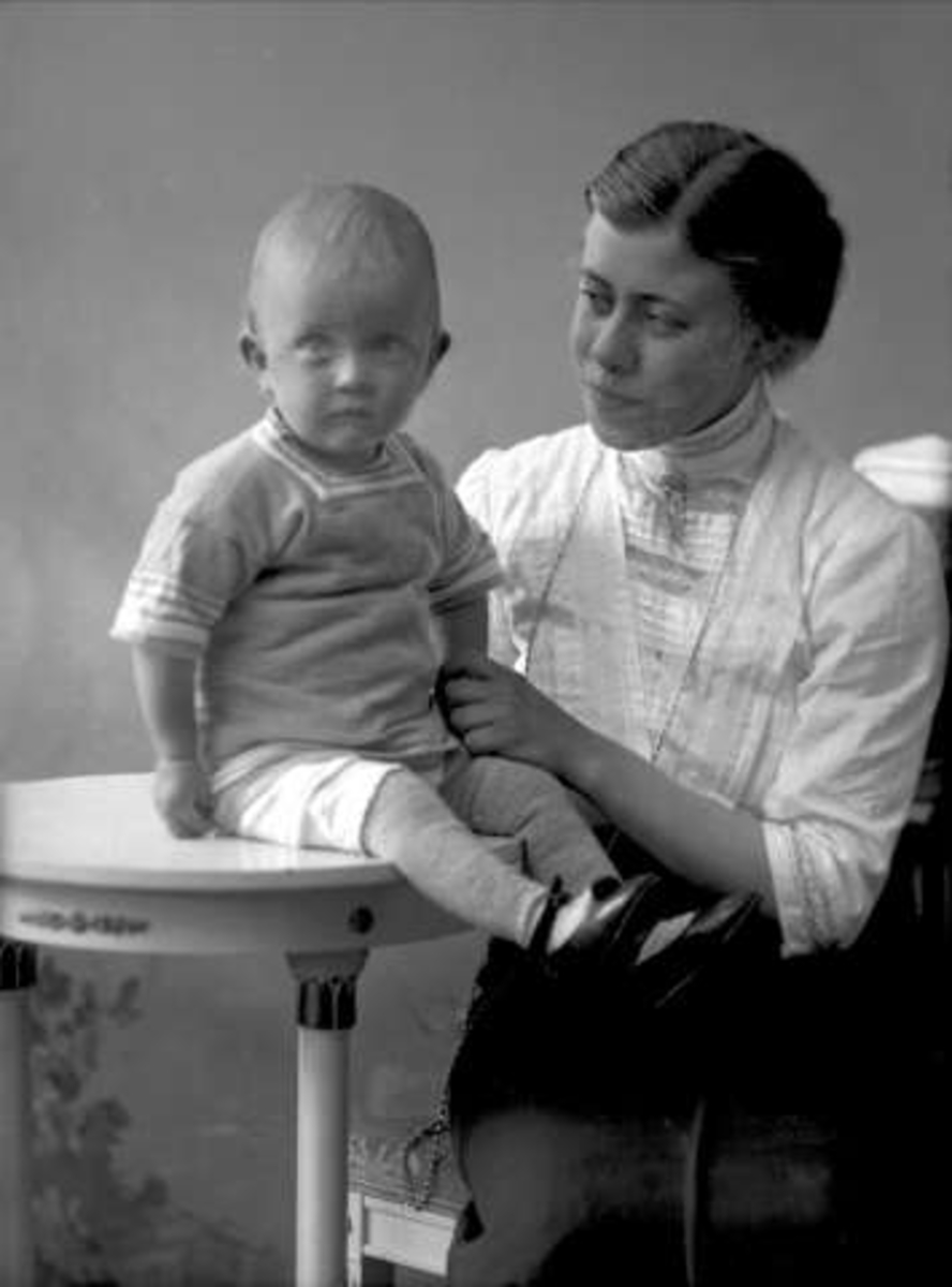 Gustav Borgen, Gruppeportrett, sittende kvinne med lite barn foran seg, sittende på et bord. Fru sekretær Hauge.