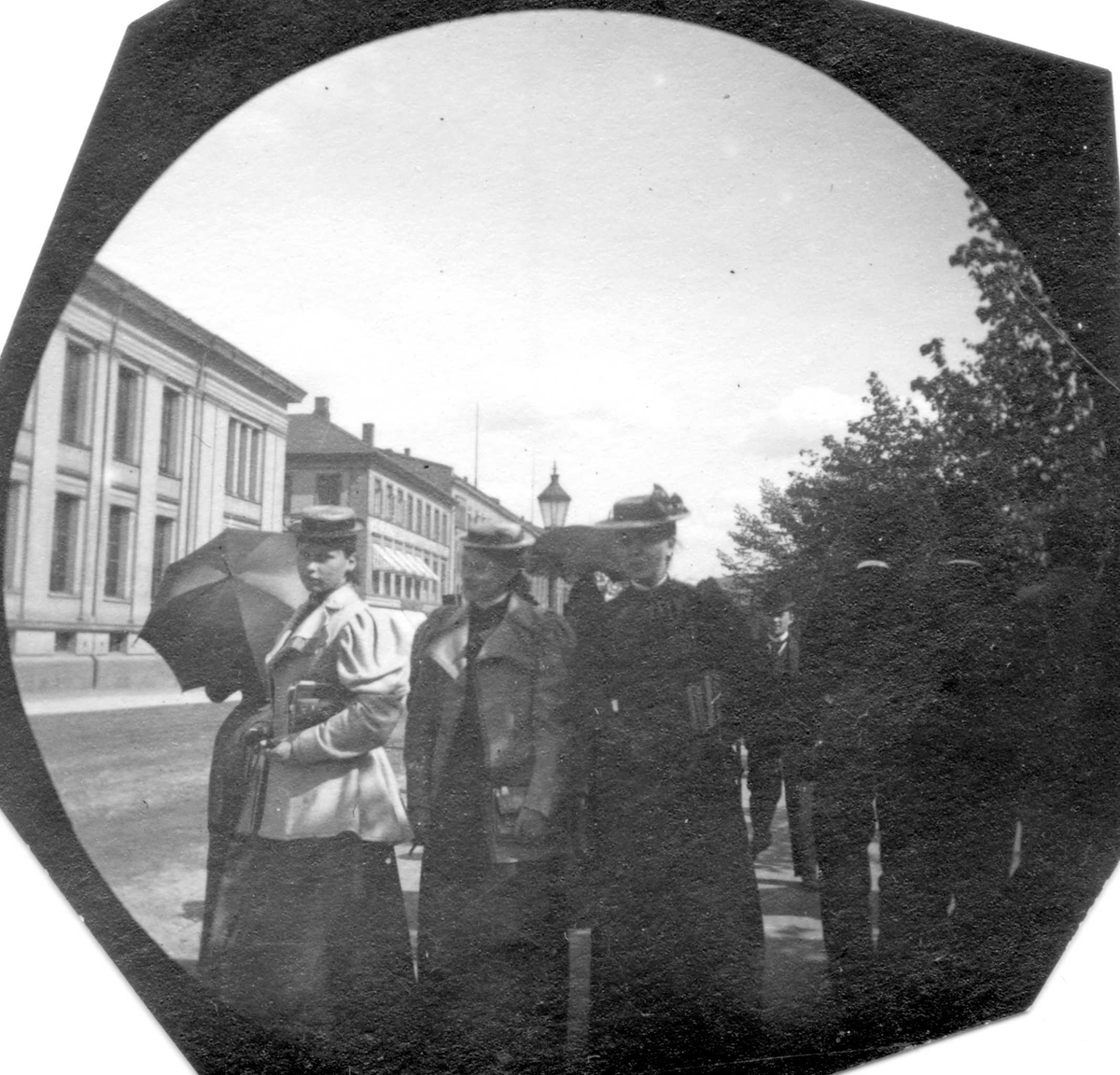 Fredrik Carl Mülertz Størmer, Frk. Hanestad til venstre, og mennesker spaserer langs Karl Johans gate, Oslo, i Studenterlunden, Universitetet i bakgrunnen..