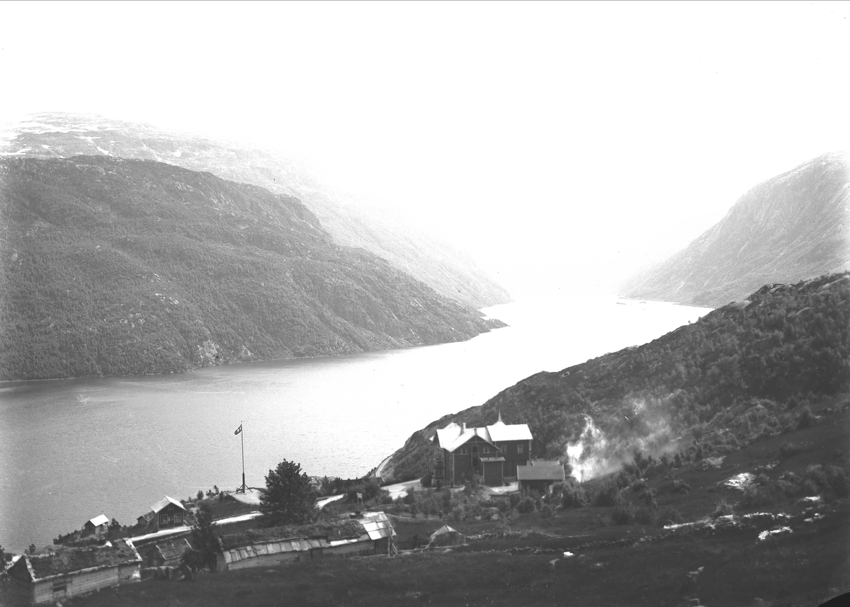 Solveig Lund, Landskapsfotografi. Fjell, fjord og bebyggelse. Breifonn i Odda med Røldalsvatnet i bakgrunnen.