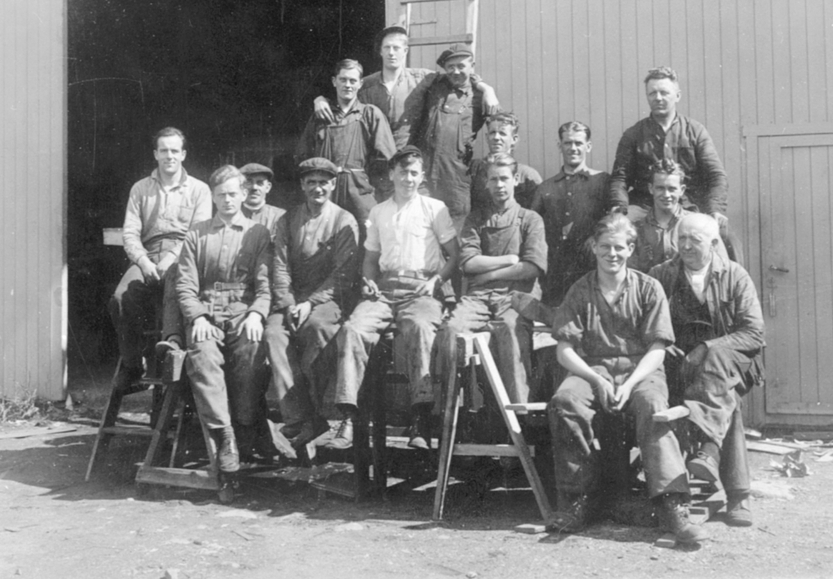 Anno Domkirkeodden, Gruppe arbeidere oppstillt utendørs ved Hymas A/S, Brumunddal Mekaniske Verksted og Støperi. Nr. 2 fra høyre i bakre rekke: Johannes Løvberg f. 15.03.1901 i Furnes. Andreas Hansen, Joh. Tollefsen, Ludvig Andersen, Ludvig Lassesen, Kristian Lilleøen, Sverre Larsen, Bekkevold, er noen av de øvrige pe…
