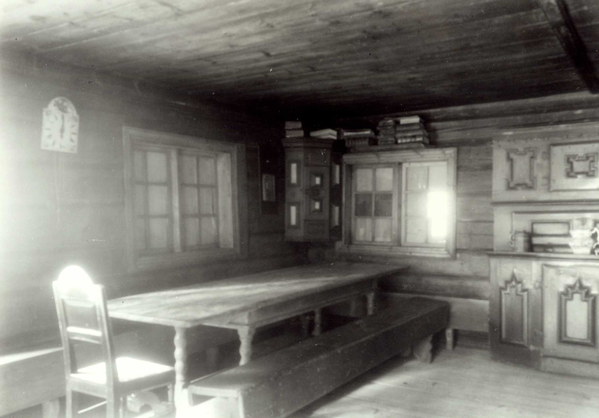 Gisle Midttun, Vesterhaug, Elverum, Sør-Østerdal, Hedmark. Interiør med veggklokke, skap, stol, bord og benk. Nå på Glomdalsmuseet.