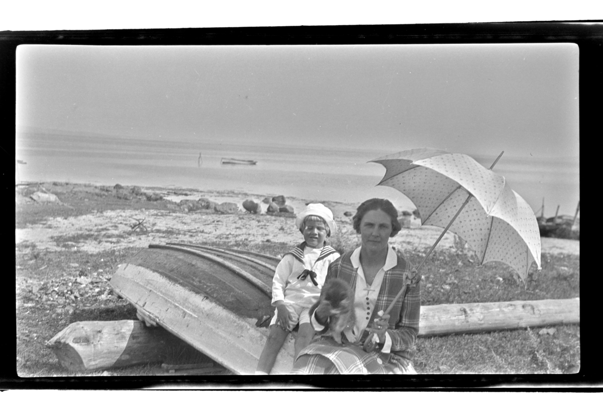 Rolf Sr. Sundt, Hilda Sundt, med parasoll, og sønnen Rolf Jr. sitter på en robåt på en ukjent strand. Fotografert ca. 1929.