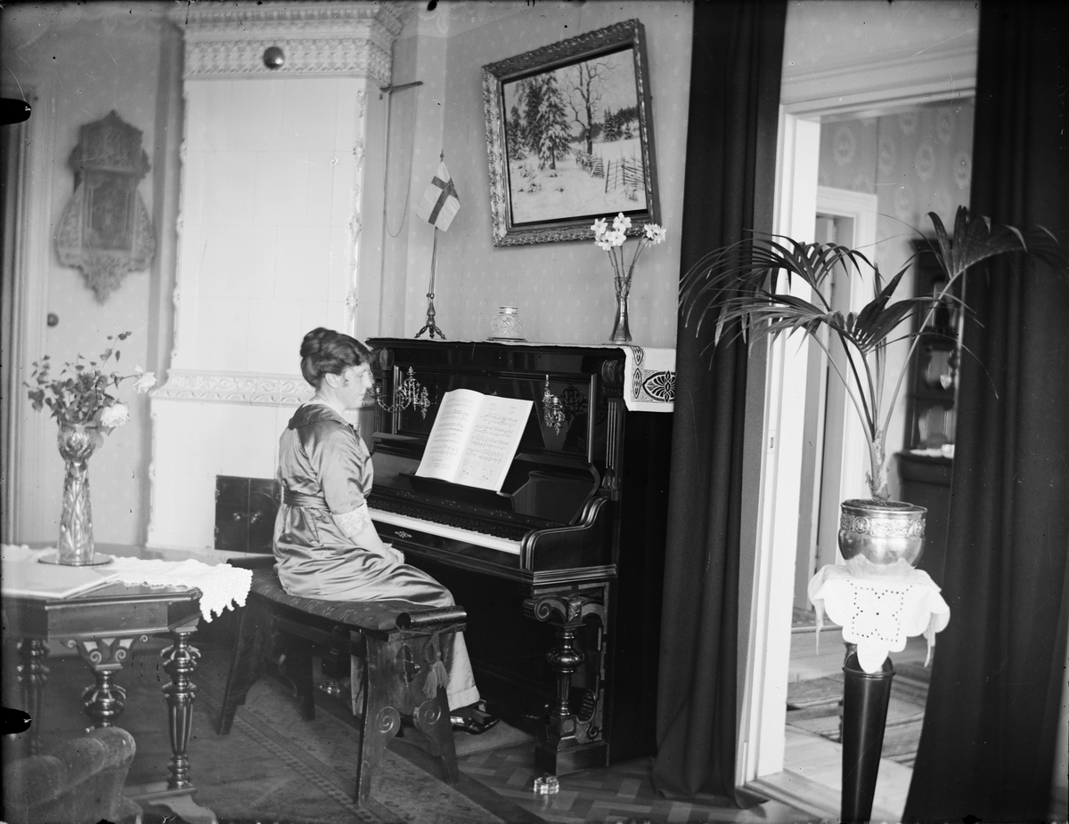 Skötsner-Edhlund, Kvinna sitter vid ett piano i bostadsmiljö, Östhammar, Uppland