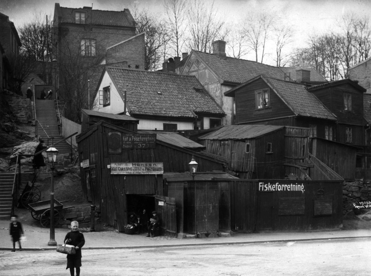 Anders Beer Wilse, Damstredet, Oslo, 1917. Trehusbebyggelse, gatebilde med trapper, lykt og fiskeforretning.