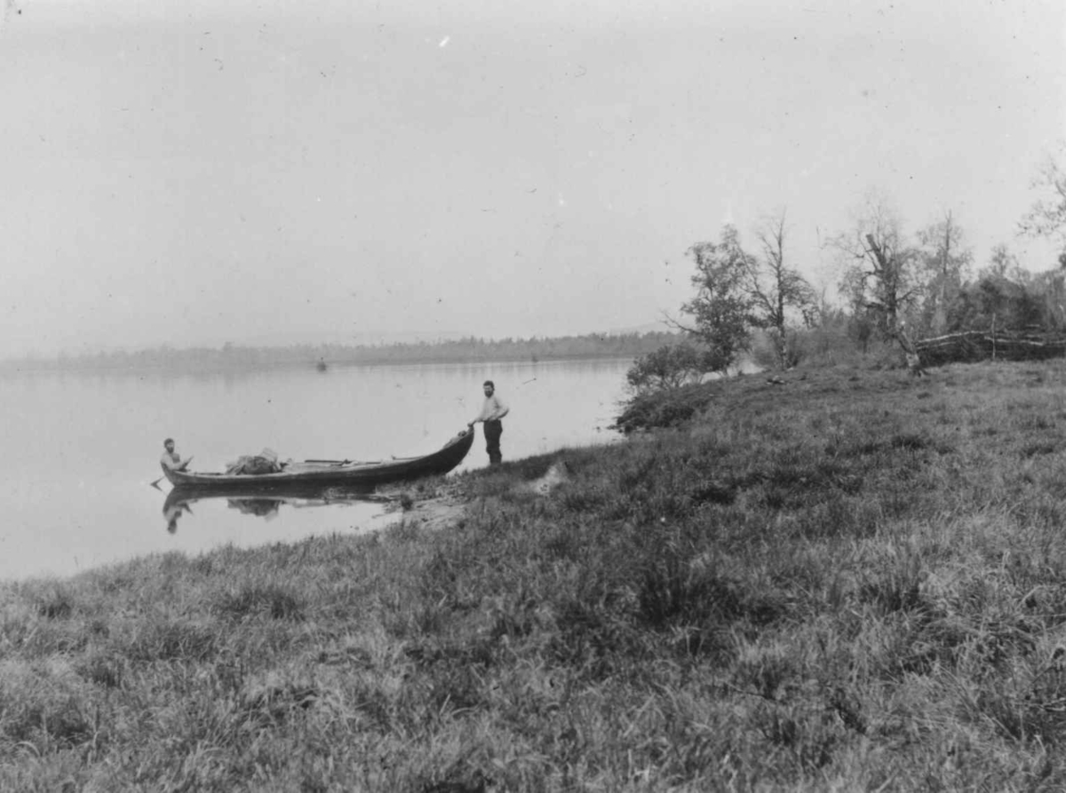 Ellisif Rannveig Wessel, To personer ved elvebåten som venter på herskapet, Svanvik, Salmijarvi, Sør-Varanger, Finnmark, 1890-årene.