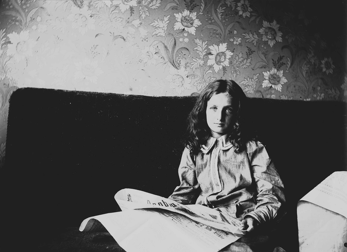 Axel Quinsgaard Wiborg, Karen Q. Wiborg leser avisen.i sofa, Prinsens gate 23, Oslo, 1906.