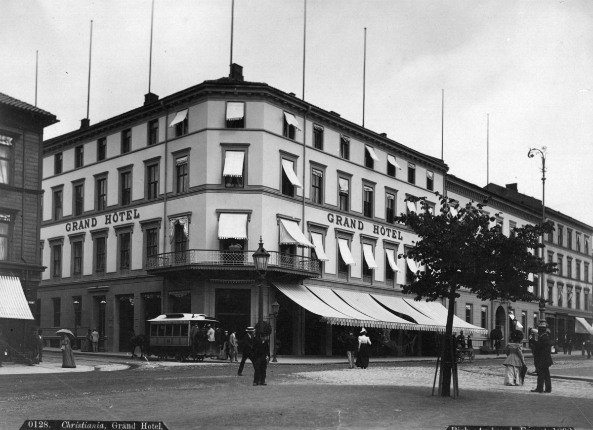 Axel Lindahl, Grand Hotell, Karl Johans gate, Oslo. Hjørnet av Karl Johans gate og Rosenkrantzgate. Gatebilde med hotellet og trikk.