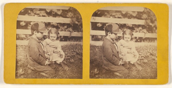 Unknown, [Little boy and girl posed on grass near fence]