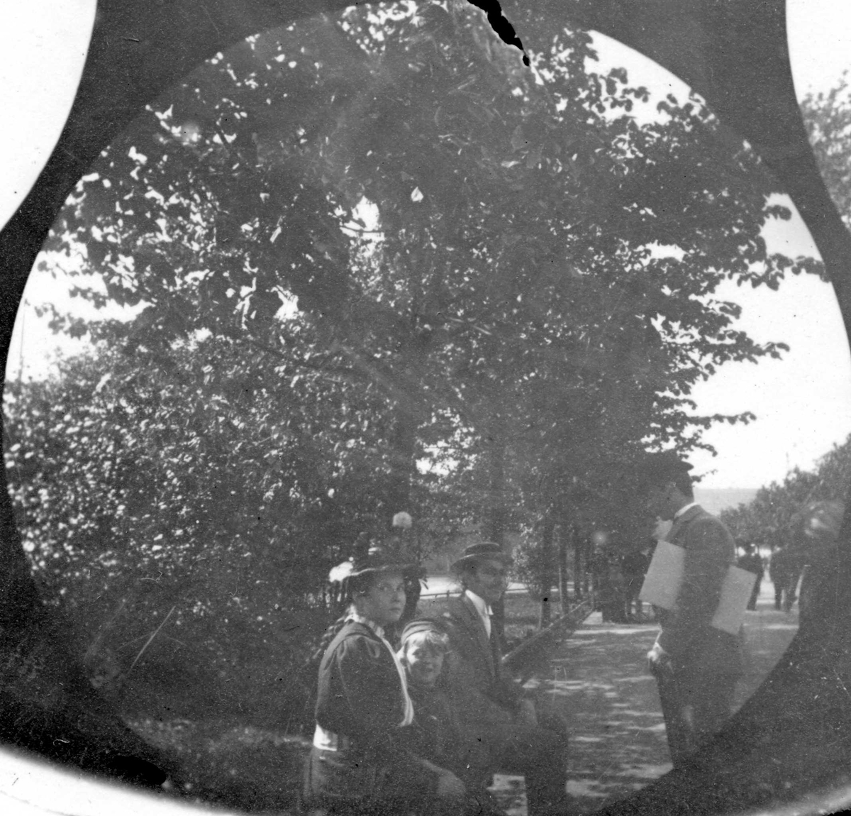 Fredrik Carl Mülertz Størmer, Mann, dame og et barn sitter på parkbenk. Mann står og prater.