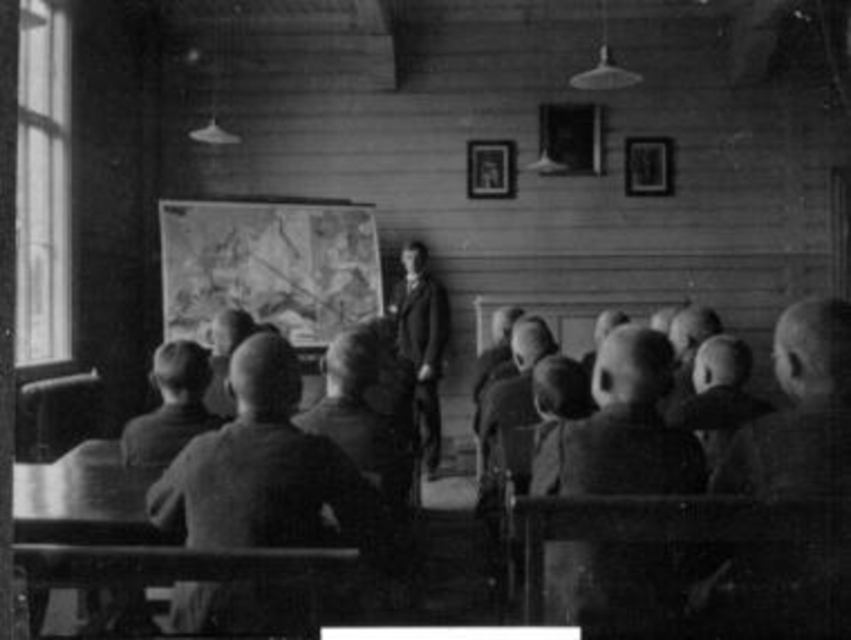 Anno Domkirkeodden, Interiør fra klasserom på Toftes Gave, Nedre Sund, Helgøya. Lærer underviser elever i geografi med kart.