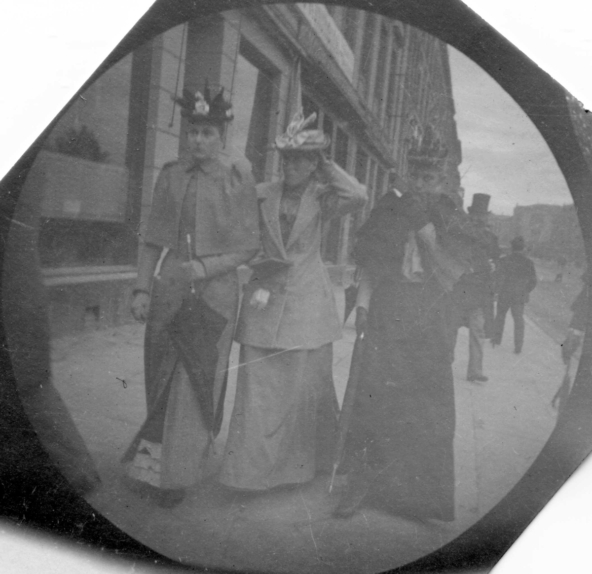 Fredrik Carl Mülertz Størmer, Frk. Johanne Irgens og to andre damer spaserer langs Karl Johans gate, Oslo, med Stortinget i ryggen.