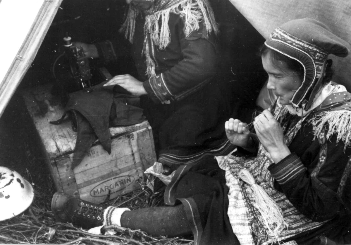 Anna Grostøl, En kvinne bearbeider senetråd og en annen kvinne syr på symaskin. Olderdalen, Kåfjord, Troms 1947.