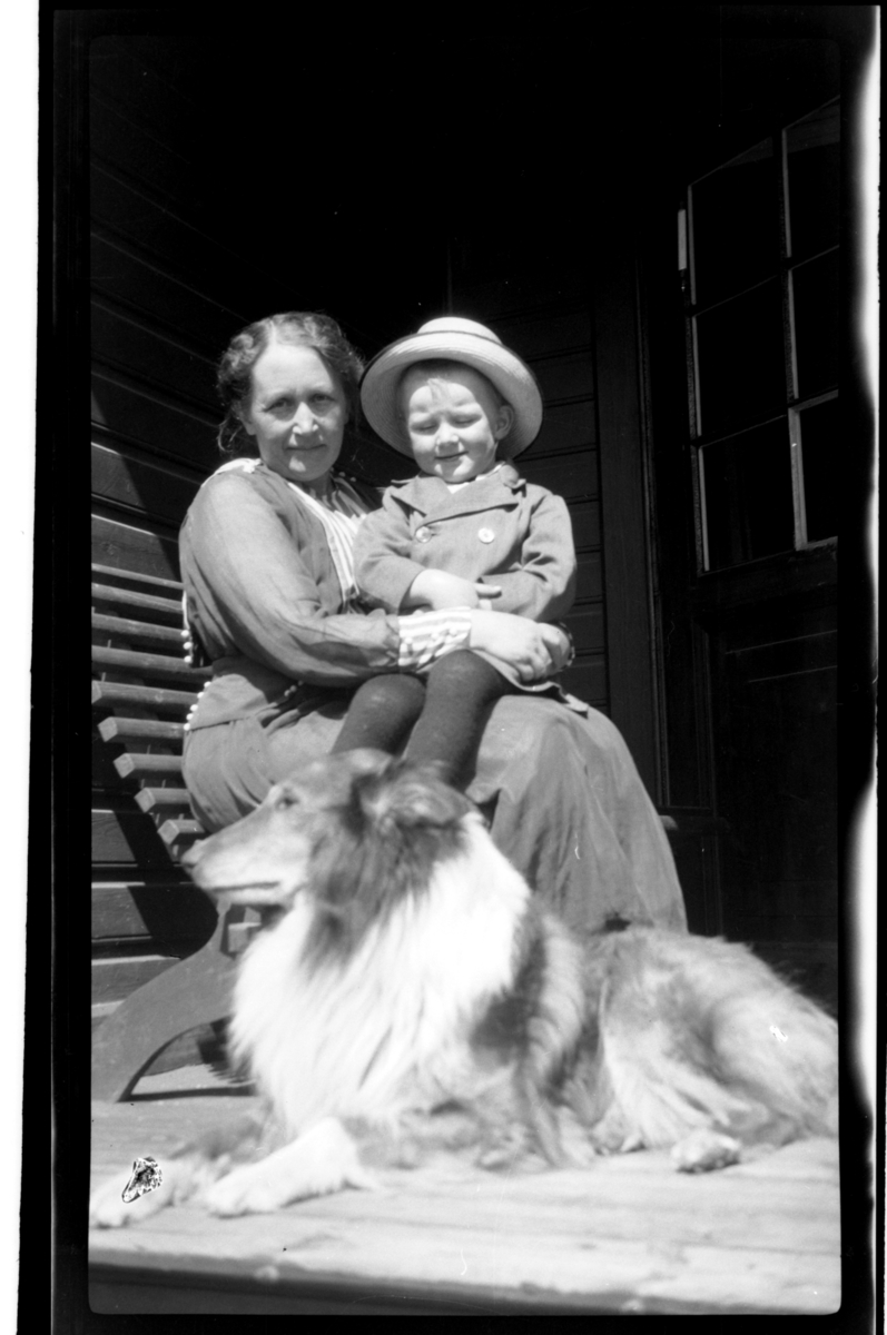 Rolf Sr. Sundt, Rebekka Sundt har sin nevø Julius Sundt på fanget mens hunden Scott ligger på gulvet, Stavern. Fotografert ca. 1922.