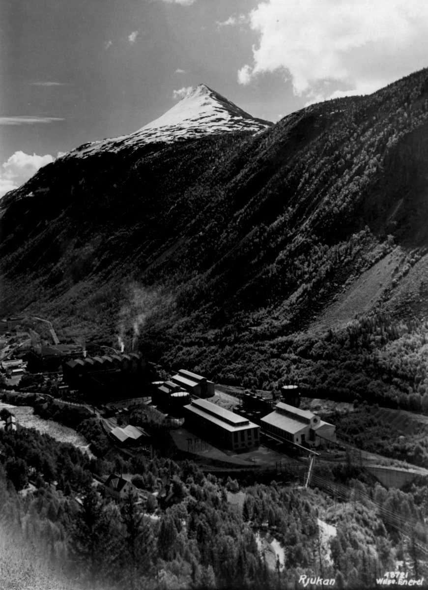 Anders Beer Wilse, Fabrikkbygningene i "Nyanlegget" (ca. 1930) på Rjukan. Rjukan i Vestfjorddalen i Tinn. Gausttoppen i bakgrunnen.