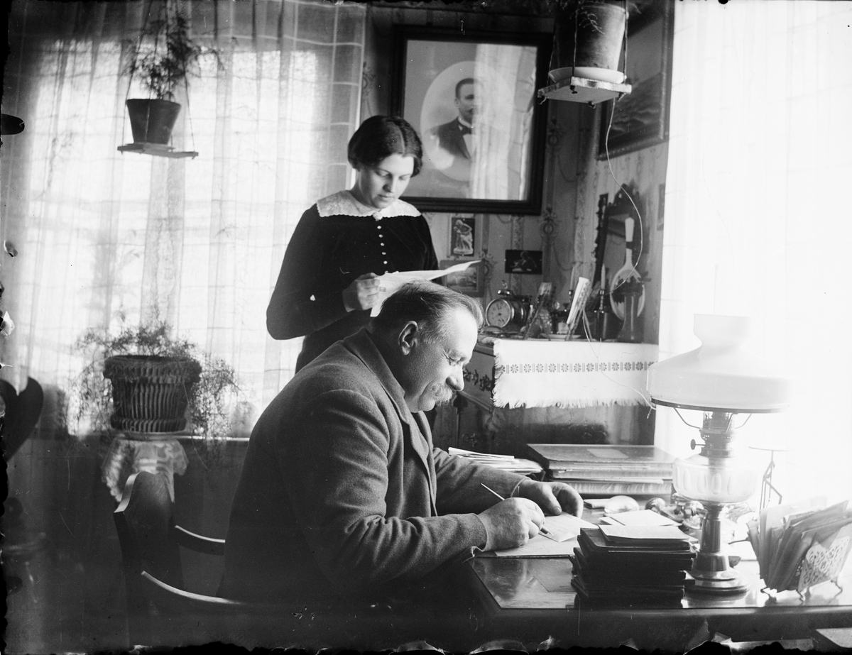 Skötsner-Edhlund, A G Borg sits at the desk and “Tilan” Borg stands next door with a paper in his hand, Sanda, Harg parish, Uppland