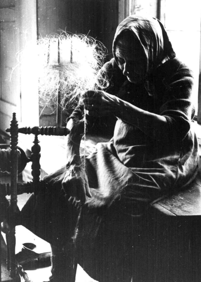 Anna Grostøl, Iveland, Vest-Agder 1941. Guri Neslebø spinner kutagl på håndrokk.