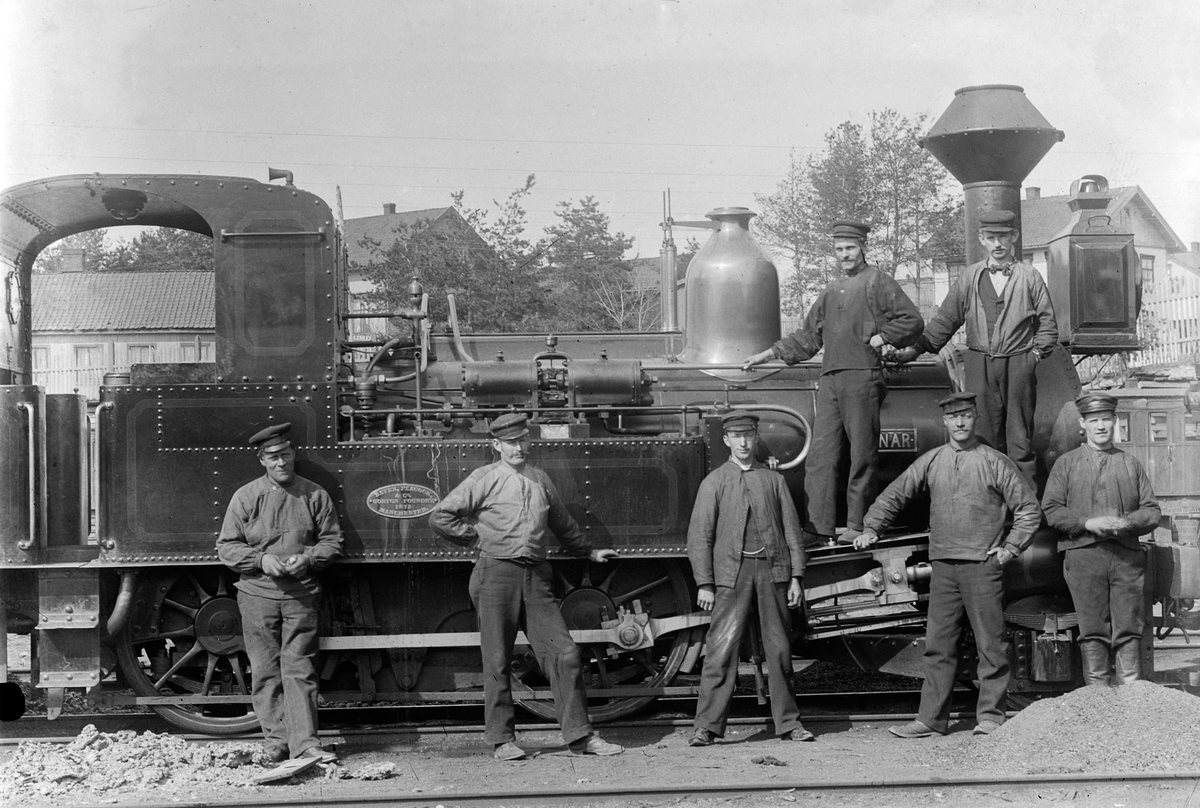 Ragnvald Andersen, Gr 7. Sju menn foran damplokmotiv, Hamar stasjon. Lokomotiv Einar, produsert av Beyer Peacock & Co, Gorton Foundry i Manchester i 1873. F. v. står Mikkel Haug, Bernt Julius Andreassen, Jens Kraft Lund, de to andre er ukjente. De to som står på lokomotivet er Bersvent Skreden og Johan Eriksen.